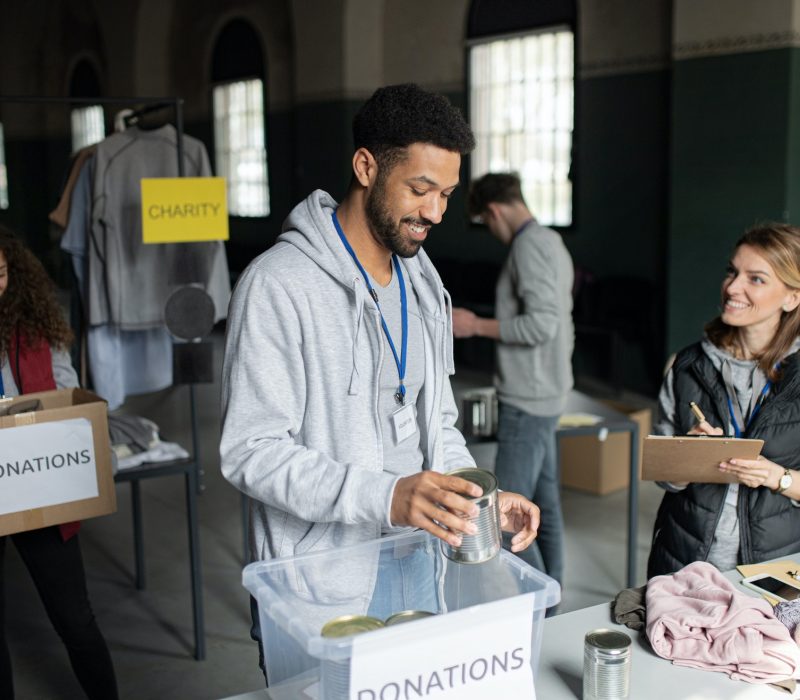 Volunteers working in community charity donation center., sorting out clothes and canned food.